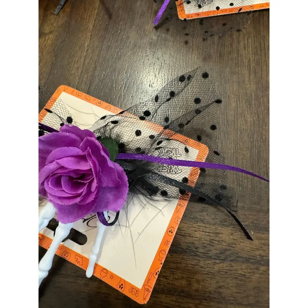 Purple rose hair clip with black netting and purple ribbon on a skeleton hand